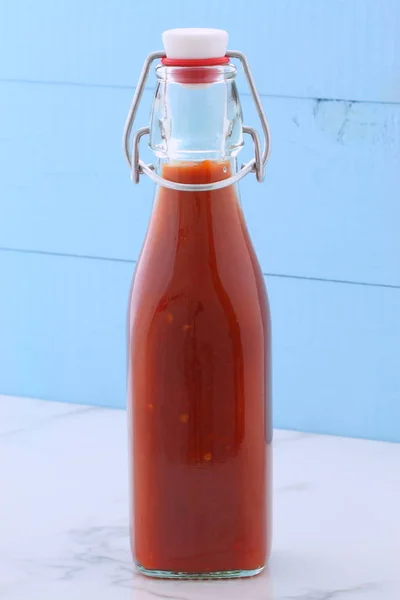 Artisan mexican red hot sauce on retro vintage carrara marble in antique bottle, perfect for all your Mexican, tex-mex recipes and sides.
