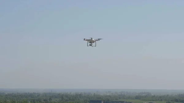 Летящий вертолетный дрон на фоне белых облаков — стоковое фото