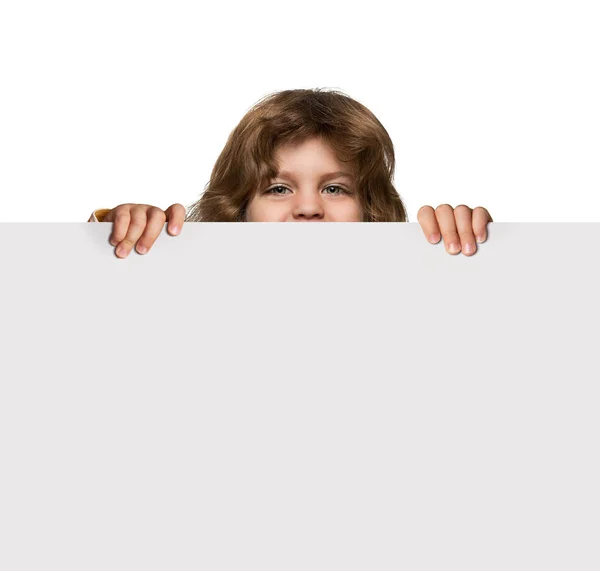 Симпатичный мальчик прячется за пустым плакатом — стоковое фото