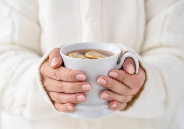 Mãos femininas segurando xícara de T quente — Fotografia de Stock