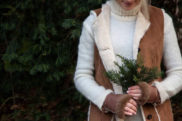 Girl in the warm, brown coat and leather gloves with fur holding spruce bouquet after harving — Stock Photo, Image
