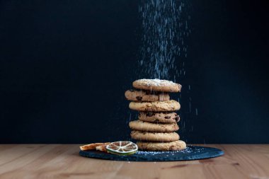 Tanımlama karanlık taş plaka ve ahşap masa pudra şekeri ile. Siyah arka plan ve bazı yan narenciye dilimleri kurutulmuş.