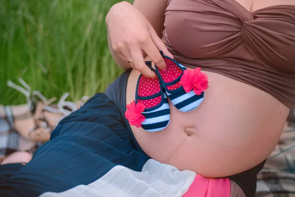 Vientre embarazada con zapatillas recién nacido —  Fotos de Stock