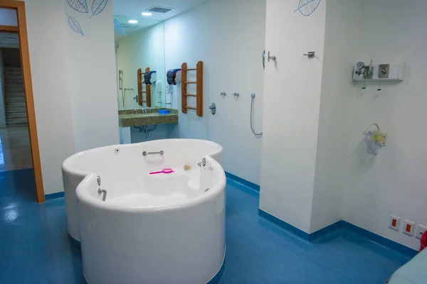 Maternity ward in a hospital with a bath for birth in water. Moderate lighting.