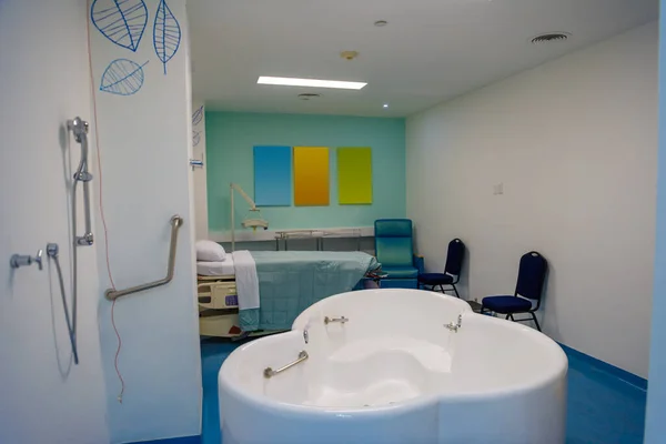 Maternity ward in a hospital with a bath for birth in water. Moderate lighting.