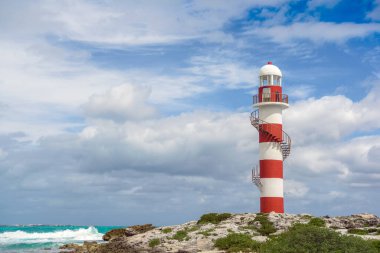 Cancun 'da kayalık bir sahilde deniz feneri. Açık gökyüzü ve mavi deniz.
