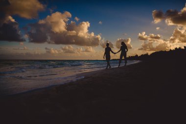 Batan güneşin arka planına karşı kadın ve erkeklerin siluetleri