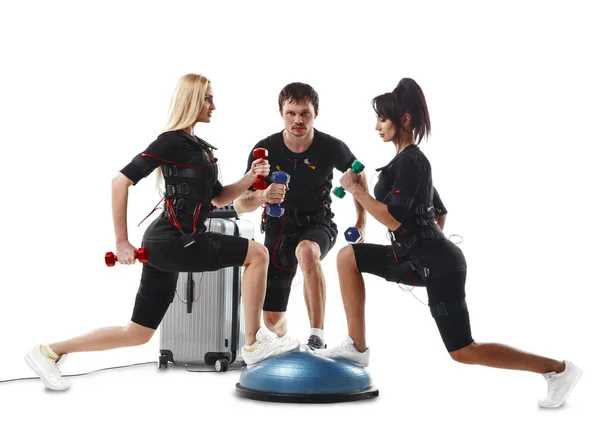 Grupo de atletas de fitness en trajes EMS haciendo ejercicio de embestida con pesas —  Fotos de Stock