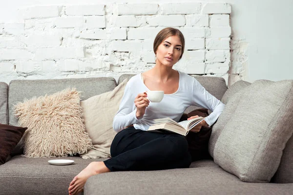 Mujer leyendo un libro en un sofá — Foto de Stock