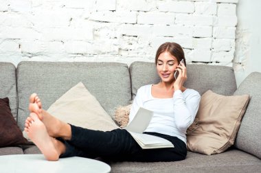 Kadın kanepede oturan cep telefonuyla söz