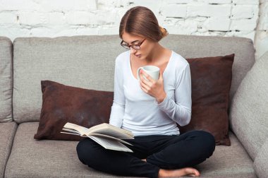 Kanepede kitap okuyan kadın.