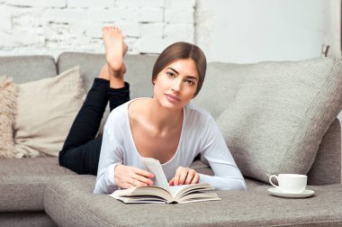 Kanepede kitap okuyan kadın.