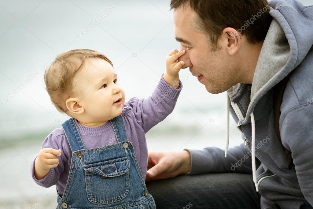 The cheerful one-year child touches his father's nose