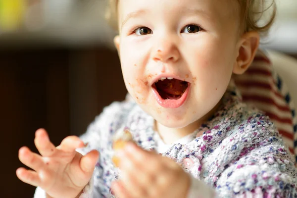 Das fröhliche kleine Mädchen isst und lacht — Stockfoto