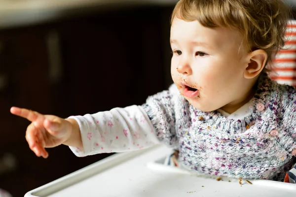 Das einjährige Kind zeigt mit dem Finger und fordert mehr Nahrung — Stockfoto
