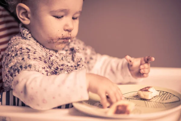Baby mit unordentlichem Gesicht isst Käsekuchen — Stockfoto
