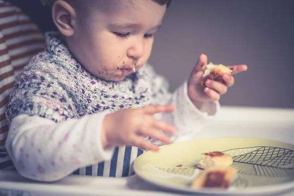 Baby mit unordentlichem Gesicht isst Käsekuchen — Stockfoto