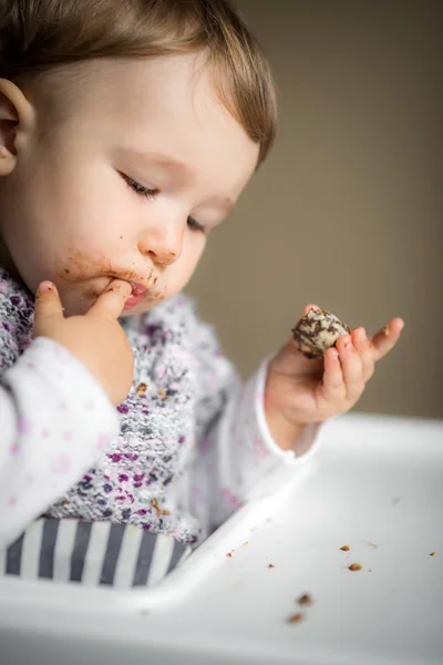 Bebé con la cara desordenada come y pone el dedo en su boca —  Fotos de Stock