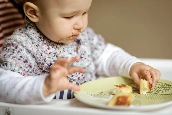 Das nette Baby mit dem unordentlichen Gesicht, das Käsekuchen isst — Stockfoto