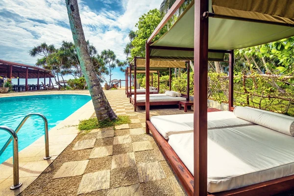 Piscine et lits de plage dans un hôtel tropical — Photo