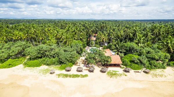Aerial view of the tropical beach with a lonely hotel in Sri Lanka. Resort beach in the sunlight. Beauriful deserted summer beach. Scenic panorama of the sandy beach. Landscape of a tropic.