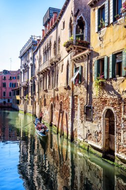 Turistli Gondol Venedik 'teki eski evlerin önünden geçiyor. Sahne