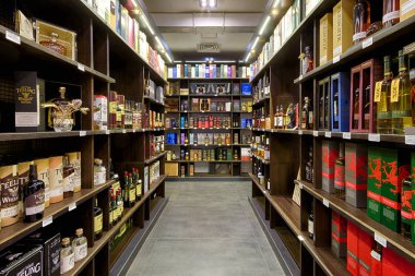 Şarap dükkanının içi. Ahşap raflarda çeşitli şarap şişeleri satılıyor. 