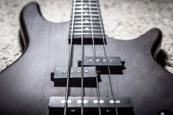 Bass guitar with four strings closeup. Detail of popular rock mu