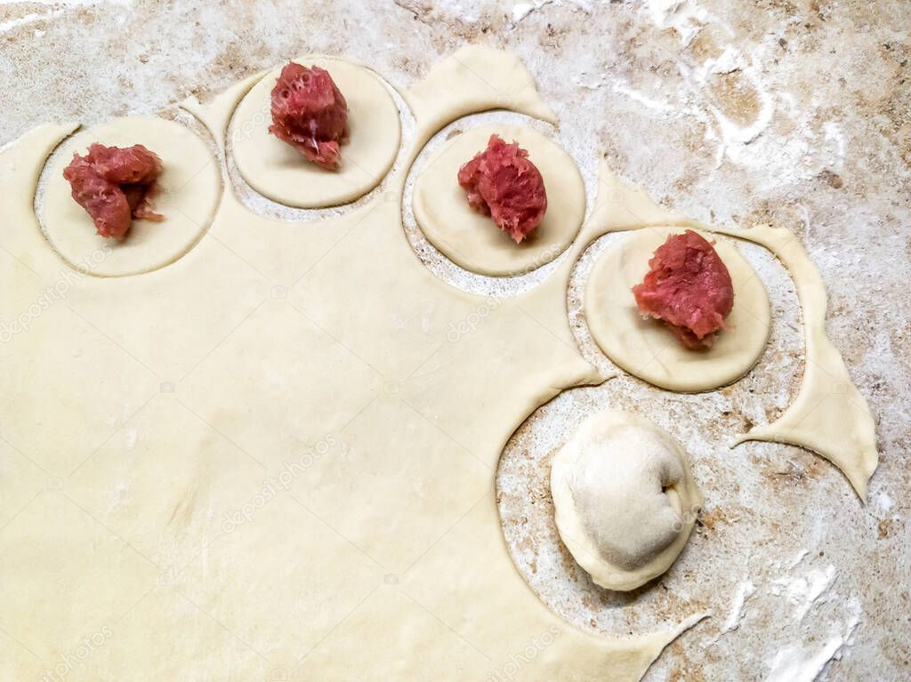 Dumplings raw and food dough on marble table, traditional making of Russian pelmeni or dumplings. Process of cooking ravioli, tortellini and pierogi with meat. Recipe of homemade food, top view.