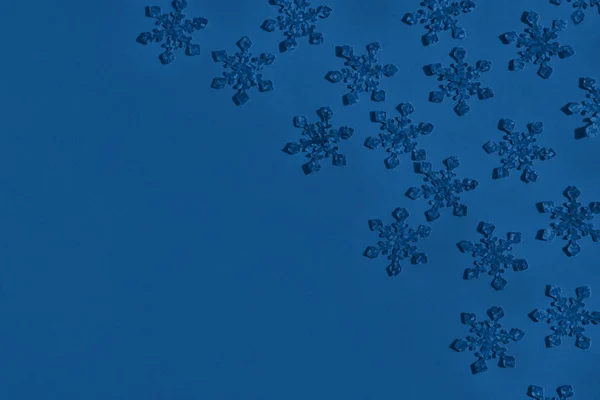Stagnola strutturata fiocchi di neve confetti sparse sul colore blu alla moda — Foto Stock