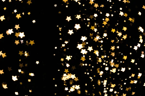 Golden stars festive glitter bokeh dark background — Stock Photo, Image