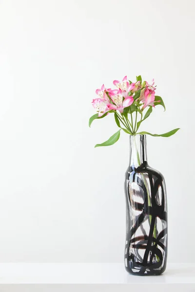 Różowa alstroemeria w szklanym wazonie na białym stole — Zdjęcie stockowe