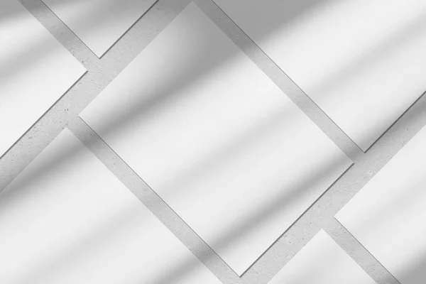 Empty white vertical rectangle poster mockups with diagonal window shadow on the wall