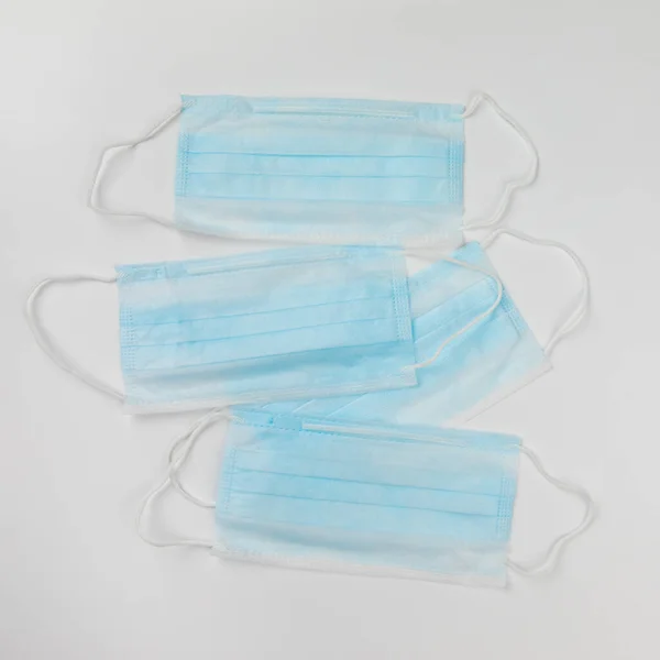 Coronavirus prevention. Typical 3-ply blue surgical medical masks lying on top of each other on white background. Hygiene corona virus protection concept. Flat lay.