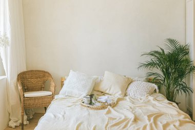 Modern romantik scandi boho tarzı yatak odası dekoratif yastıklar, yeşil bitki ve posterler için boş duvarlar. Ilık, rahat bir ev.. 