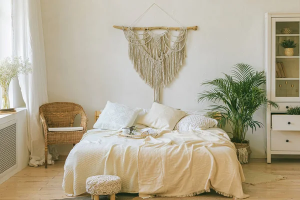 装飾的な枕 緑の植物とグレーのマクラメ壁パネルとモダンなロマンチックなスキャンディBohoスタイルの寝室のインテリア 軽い暖かい居心地の良い居心地の良い家 ジョモ週末の朝食のコンセプトは — ストック写真
