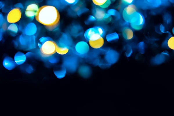 Trendy blue and yellow circles bokeh festive glitter dark background with copy space. Christmas lights bokeh overlay pattern. Modern color abstract design.