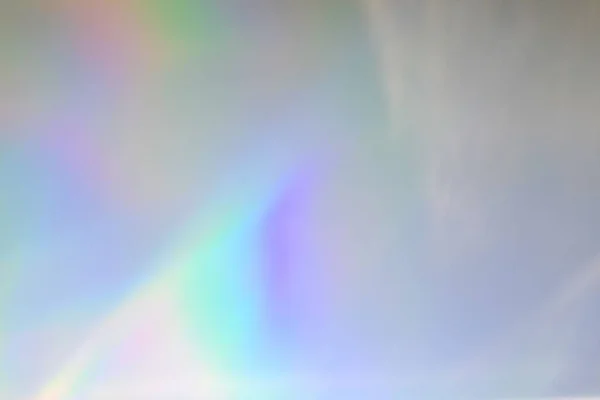 Blurred rainbow circular light refraction texture overlay effect for photo and mockups. Organic drop diagonal holographic flare on a white wall. Shadows for natural light effects