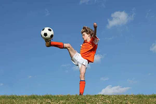 Kind spielt Fußball oder Fußball lizenzfreie Stockfotos