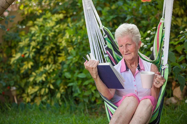 本で庭でリラックスして引退した健康なシニア女性 — ストック写真