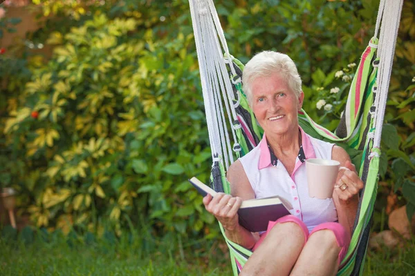 Glückliche Rentnerin Liest Gartenschaukel — Stockfoto