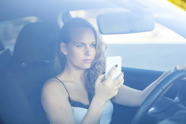 Mujer conduciendo mientras envía mensajes de texto en el teléfono celular móvil —  Fotos de Stock