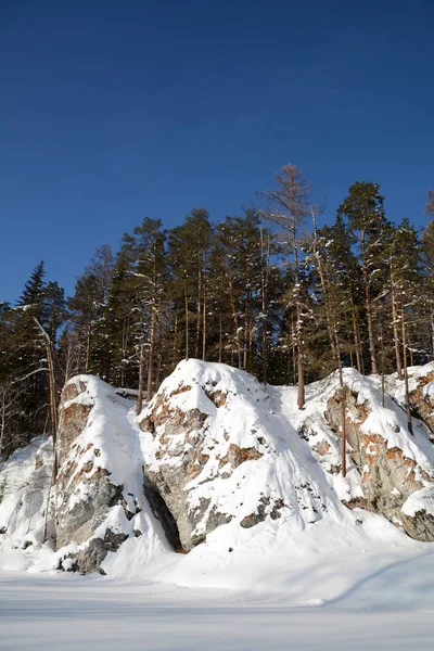 Snö-omfattas klippor på stranden av iskalla floden. — Stockfoto