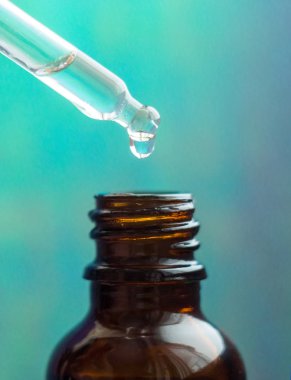 Renkli arka planda kozmetik yağ damlaları olan kozmetik pipeti. Cam damlacıktan dökülen temel yağ. Temel yağ, hyaluronik asit. Omega-3. Bitkisel özler.