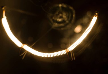 Yakından parlak bir lamba. Lamba yandı. Ampul karanlık bir odada asılı. Enerji konsepti. Ekoloji, enerji çöküşü