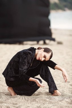 Siyah takım elbiseli, eski moda saç stili ve eski moda görüntüsü olan güzel bir genç kız.