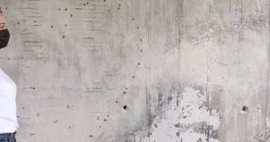 Yetişkin, gri saçlı bir adam ve bir kız birbirlerine bakıyorlar sonra siyah tıbbi maskeler ve siyah lastik eldivenlerle öpüşüyorlar..