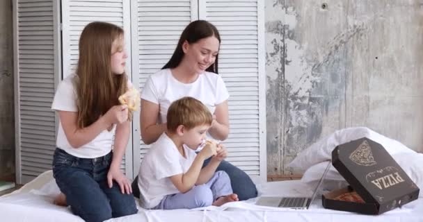 Mamá y los niños en auto-aislamiento comen pizza y ven dibujos animados en una computadora portátil — Vídeos de Stock