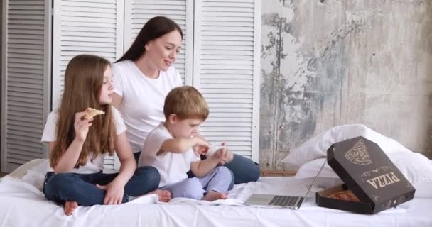 Mãe e crianças em auto-isolamento comer pizza e assistir desenhos animados em um laptop — Vídeo de Stock