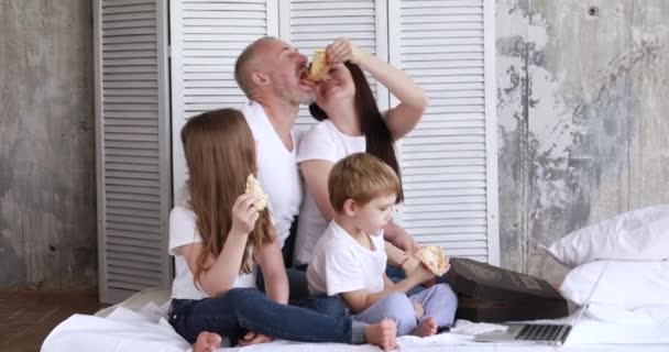 Семья дома на самоизоляции ест пиццу и смотрит мультики на ноутбуке — стоковое видео